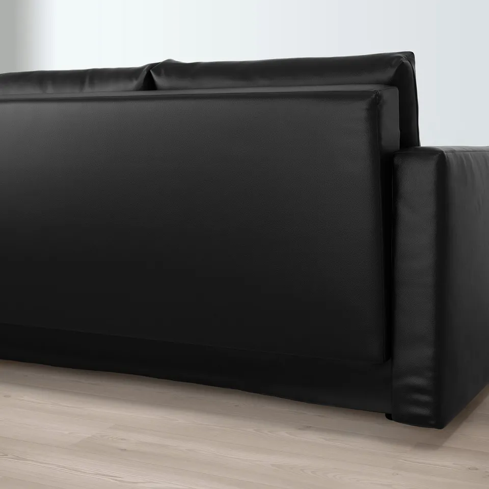 Black convertible sofa with cushions, featuring built-in storage, positioned on wooden floor.