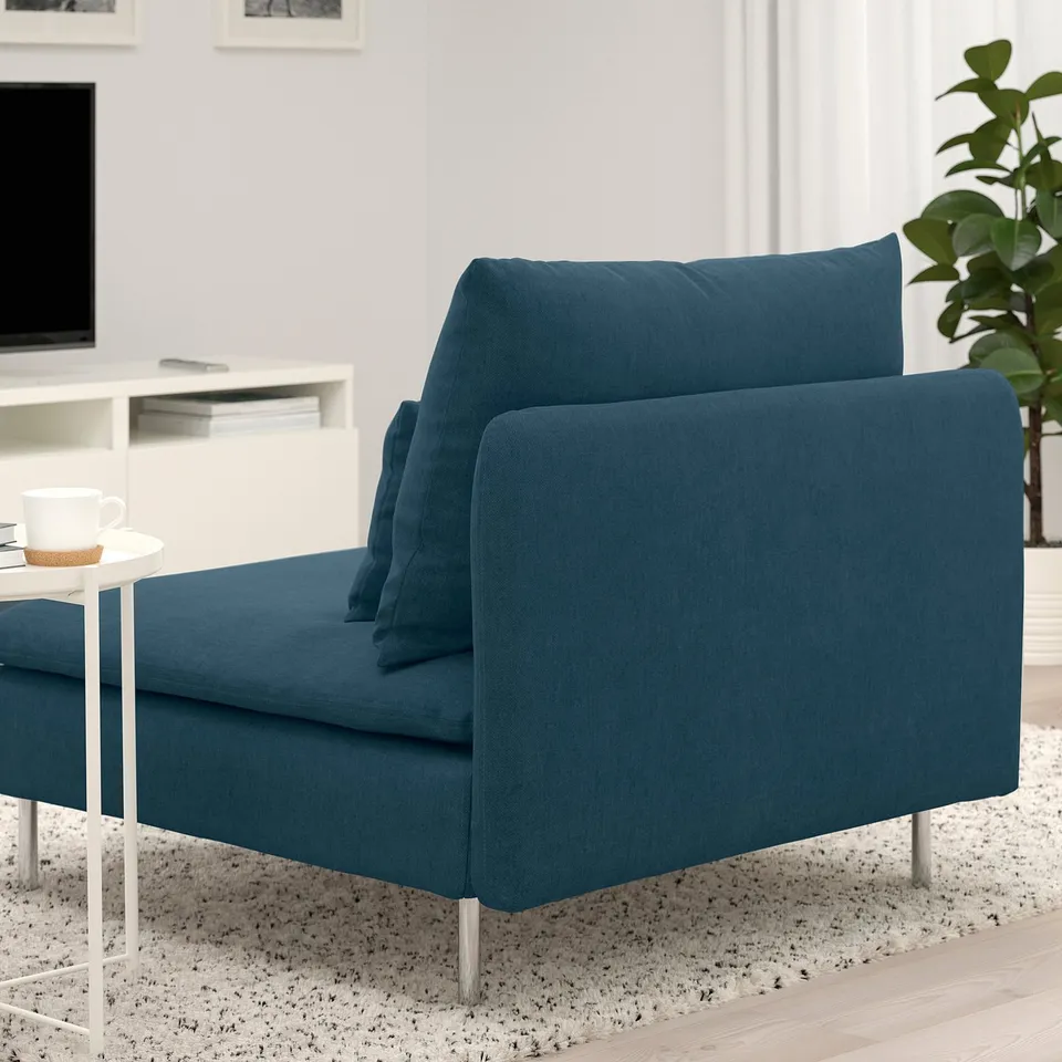 Dark blue SÖDERHAMN sectional sofa with deep seats, high legs, and loose cushions in a cosy living room setting with a coffee table and plant.