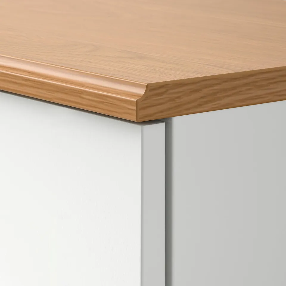 Close-up of SKRUVBY wooden countertops edge, smooth finish, light oak tone, clean joint with grey cabinet.