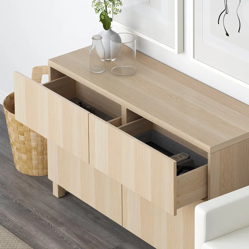 Light wood sideboard with open drawers, displaying remote and other items. Decorative vases on top.