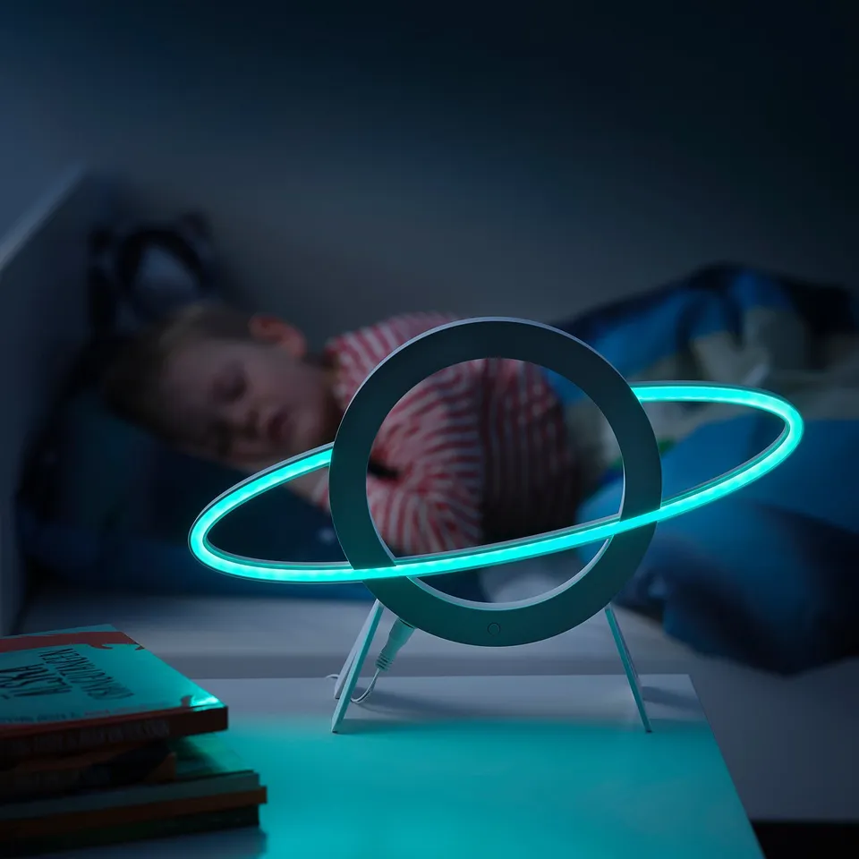 Blue led space lamp on tripod, child sleeping nearby, books beside.