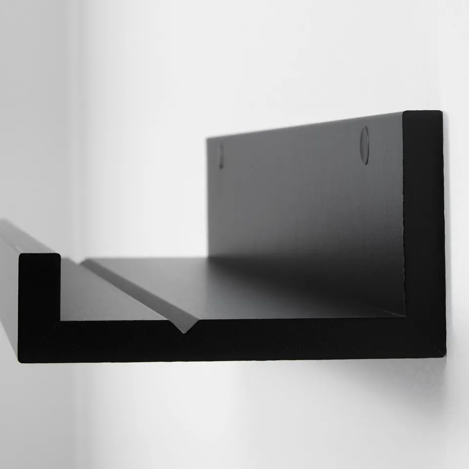 Black modern picture ledge mounted on a wall, featuring a groove for displaying small frames, with clean edges and minimalist design.