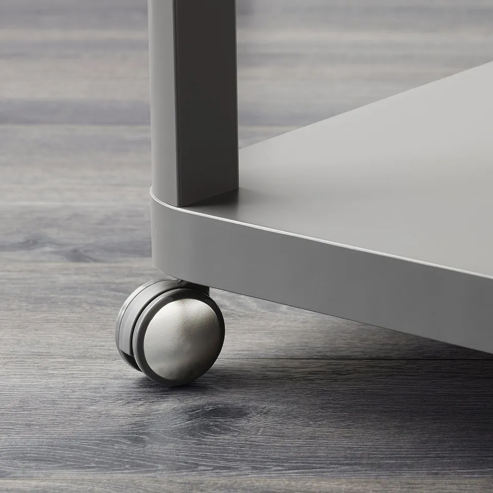 Close-up of a modern table leg with a smooth metallic finish and a roller, showcasing its sleek, stylish design.