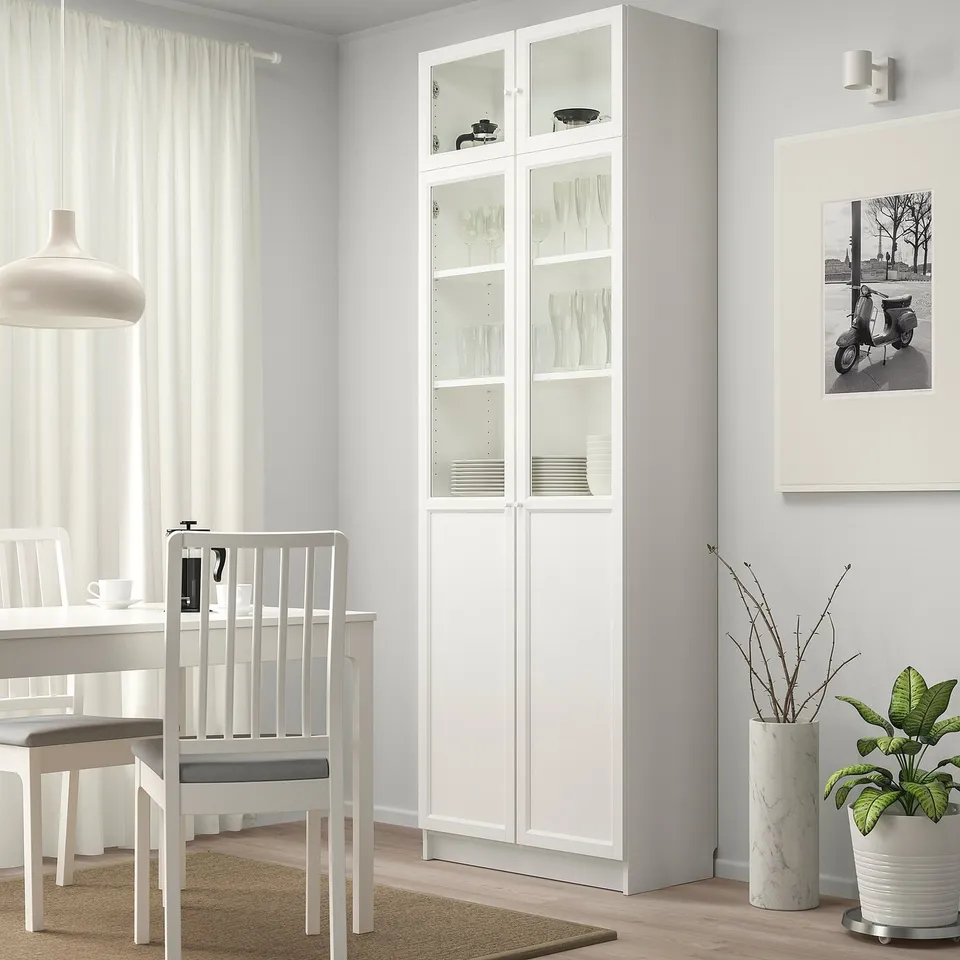 Glass-door cabinet with plates near dining table.