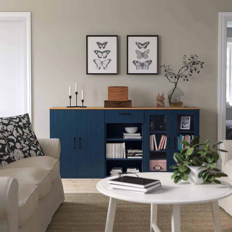 Stylish living room with blue SKRUVBY cabinet, butterfly prints, and beige couch.
