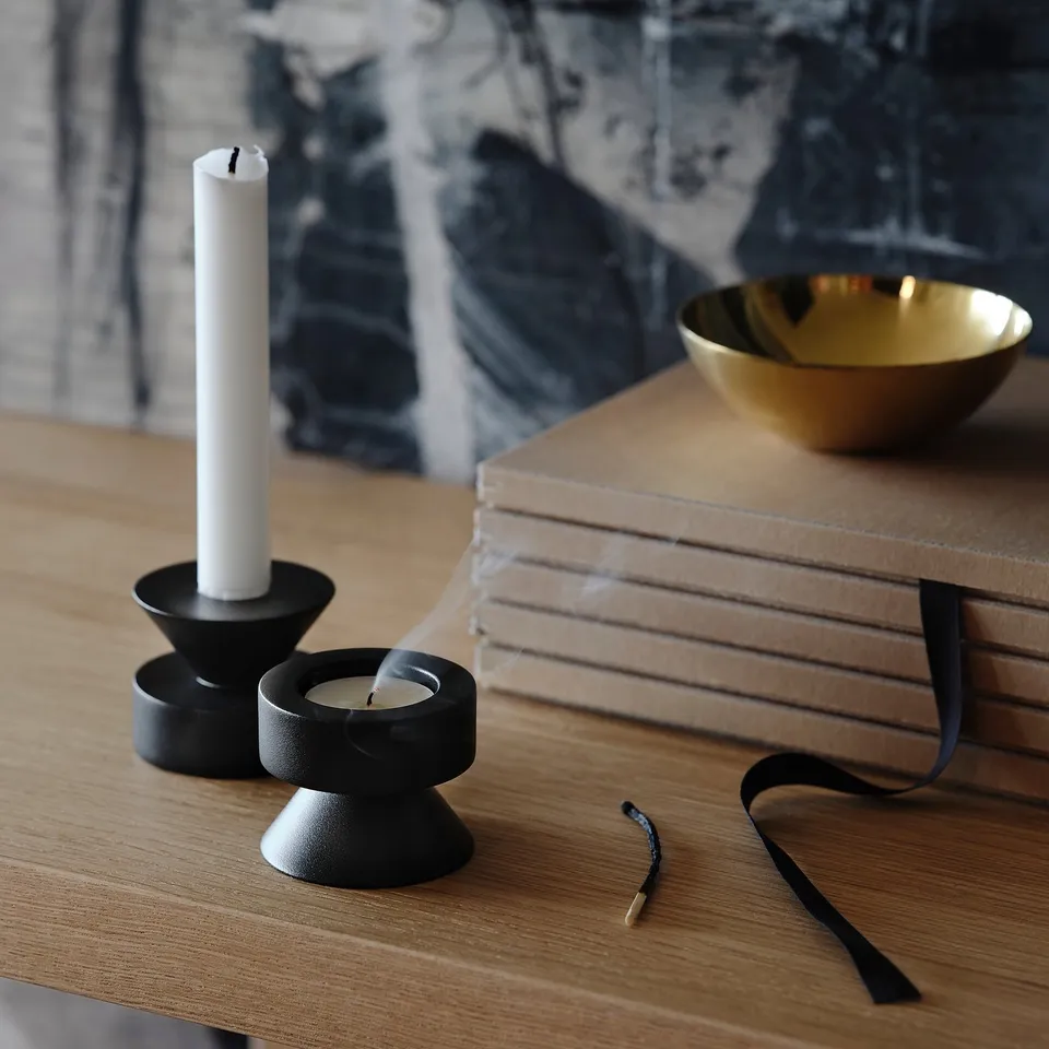 Wooden surface with candlesticks: tall and small, reversible. Golden bowl, stacked books.