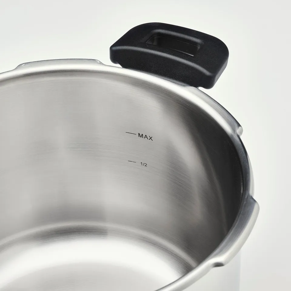 Stainless steel pressure cooker with clear max and half markings, black handle.