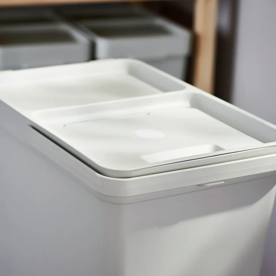 White waste sorting bin from HÅLLBAR series with lid, made of recycled plastic, featuring a folding handle and ventilation holes.