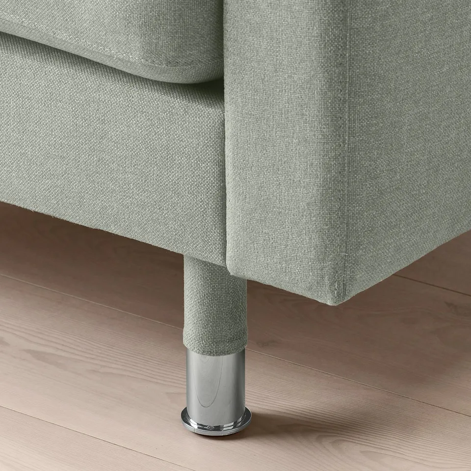 Close-up of modern, chrome-plated sofa leg with sleek, grey fabric.