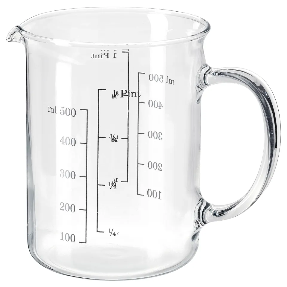 Clear glass measuring jug with handle, marked in millilitres and cups, transparent, simple design, ideal for kitchen use.