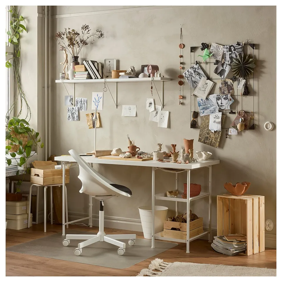 Creative workspace with white LAGKAPTEN desk, art, plants, and bulletin board.