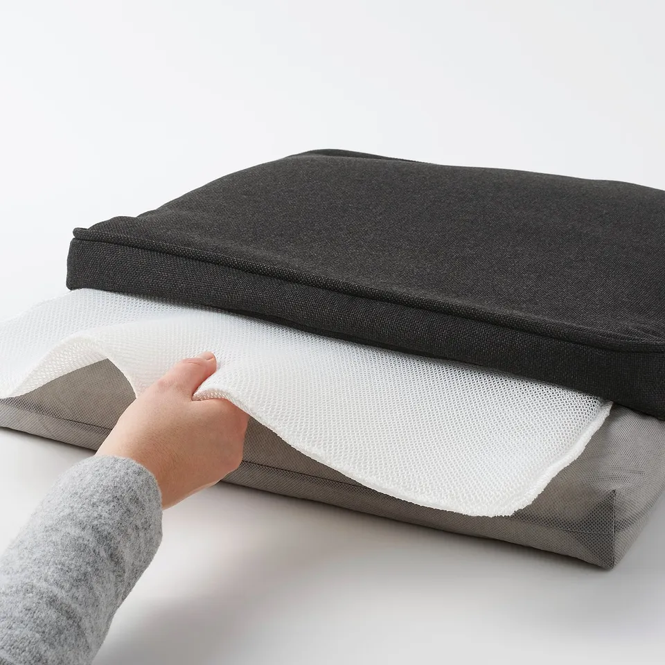 Hand placing chair cushion with non-slip mesh, demonstrating easy cover removal for cleaning.
