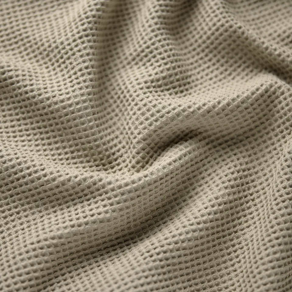 Folded beige towel, textured close-up, soft and absorbent cotton fabric.