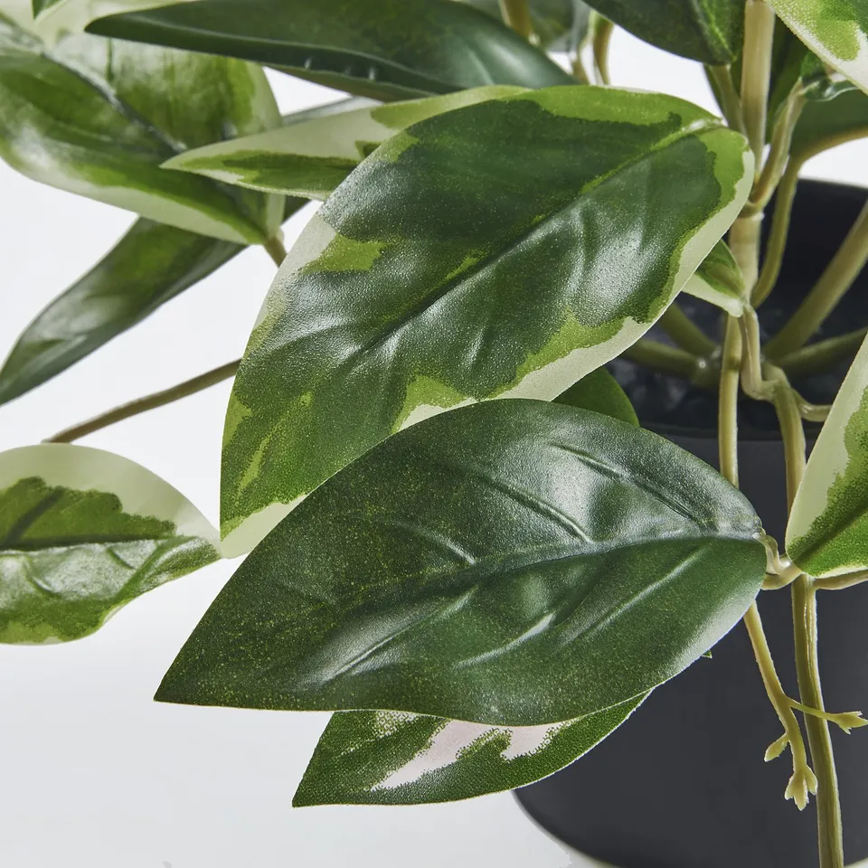 Close-up of lifelike artificial plant leaves, vibrant green, detailed veins, arranged naturally.