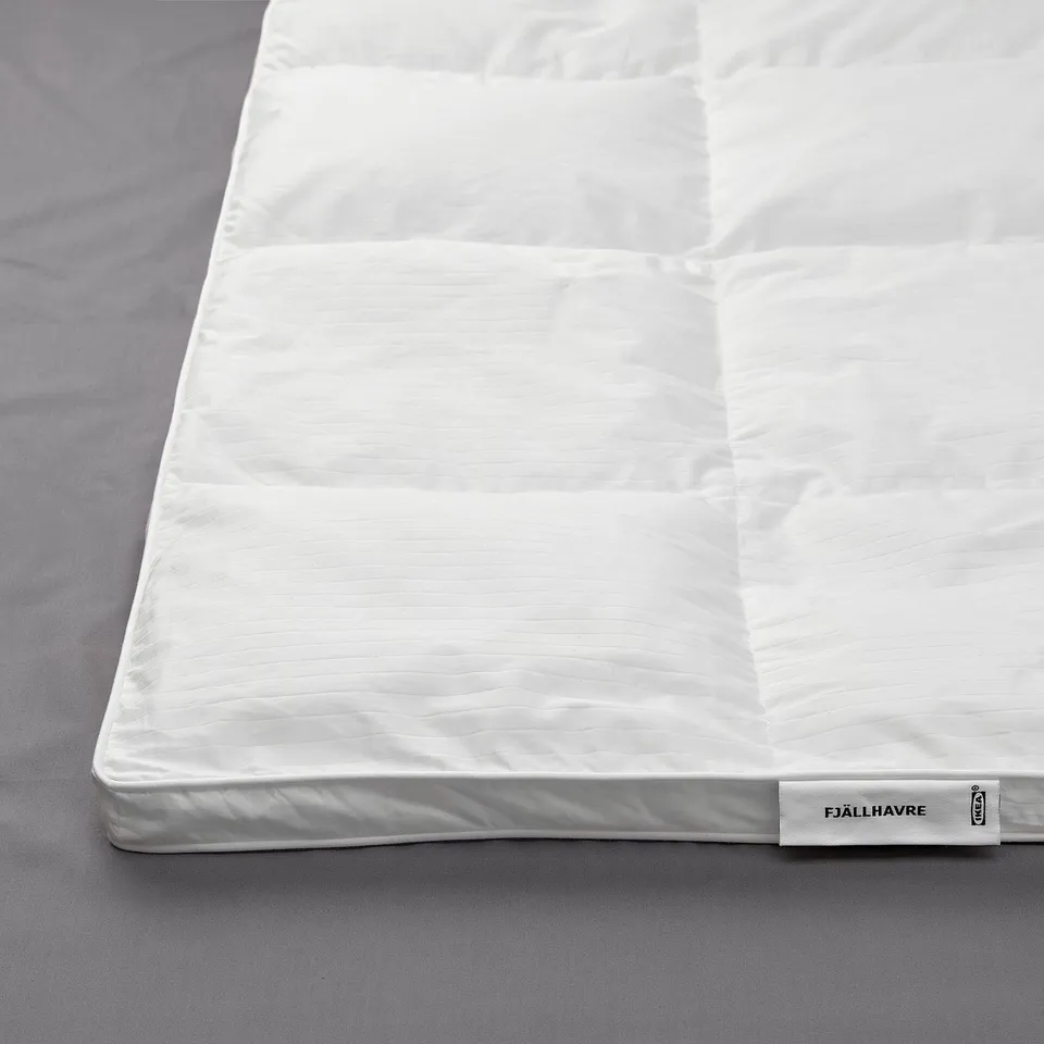 A plush, white fjällräven duvet with soft, stitched patterns, displayed on a grey fabric background, showcasing its high-quality, fluffy material.