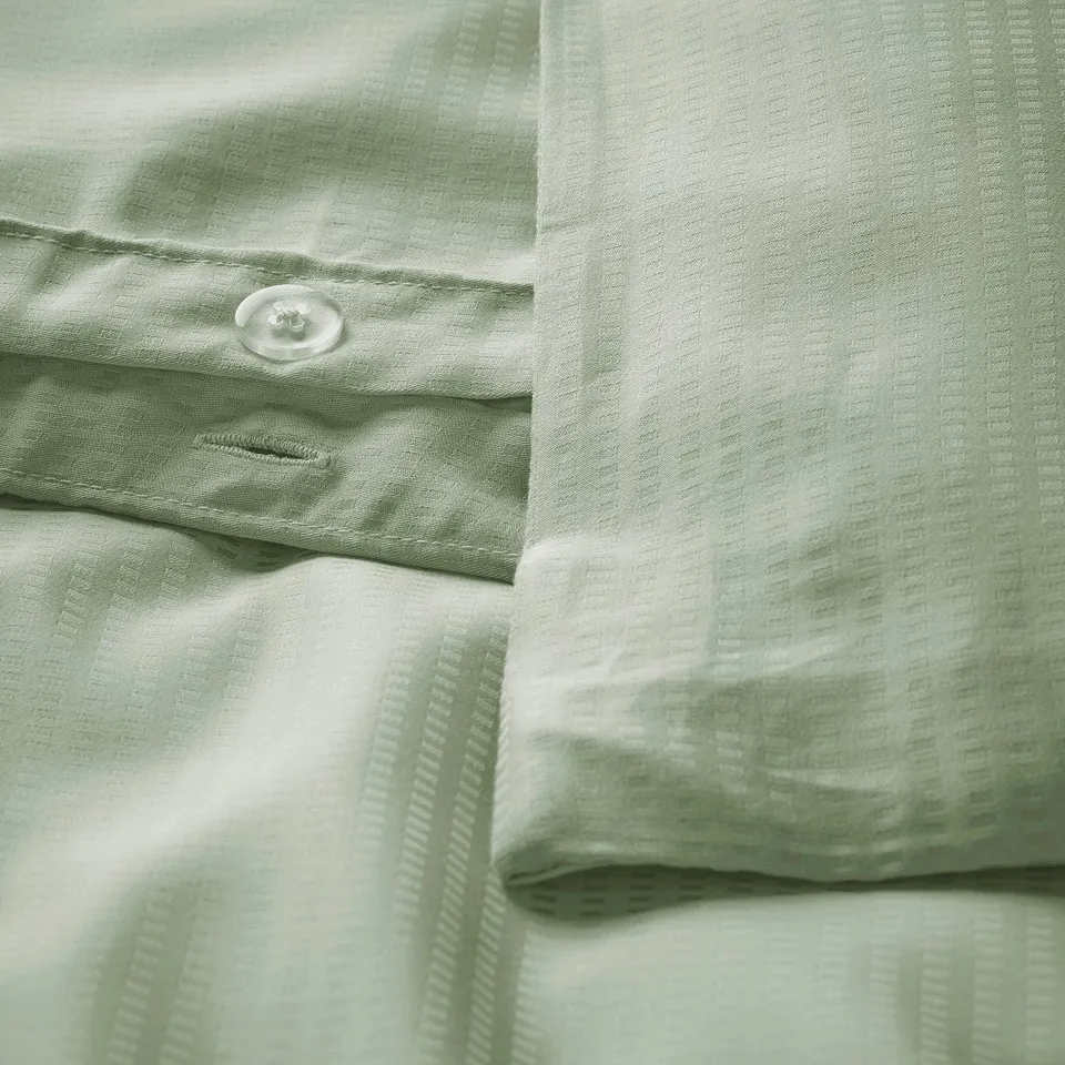 Beds green duvet cover with button closure, showing smooth, textured fabric.