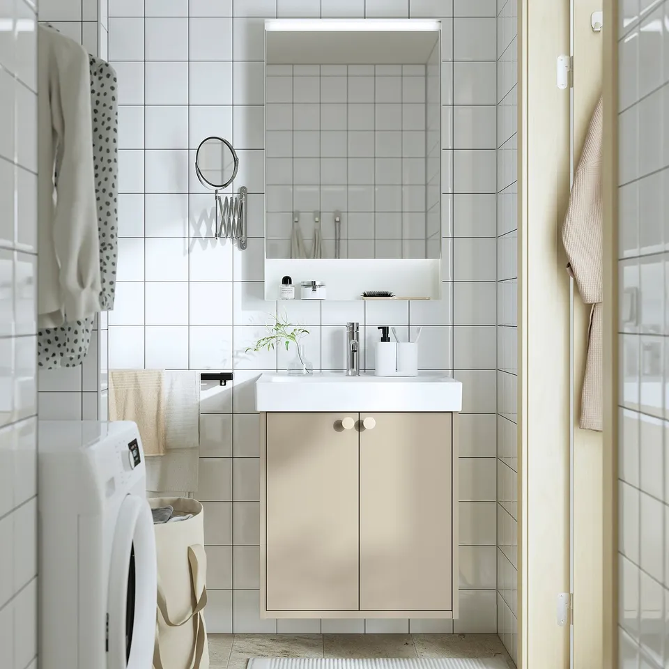 Beige HAVBÄCK cabinet with sink, storage, mirror, and lights. Includes washing machine. Minimalist bathroom setup.