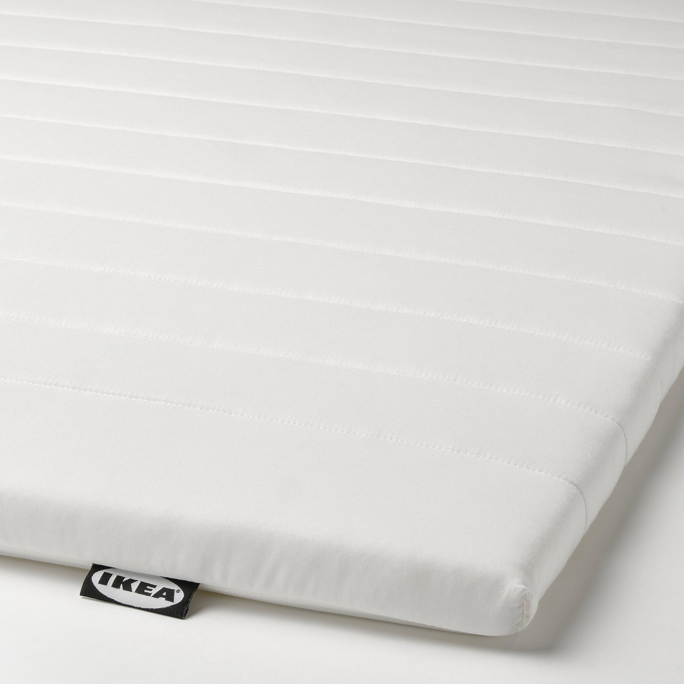 A white mattress pad by IKEA, neatly displayed, showcasing its smooth fabric and soft cushioning, with a visible brand tag.