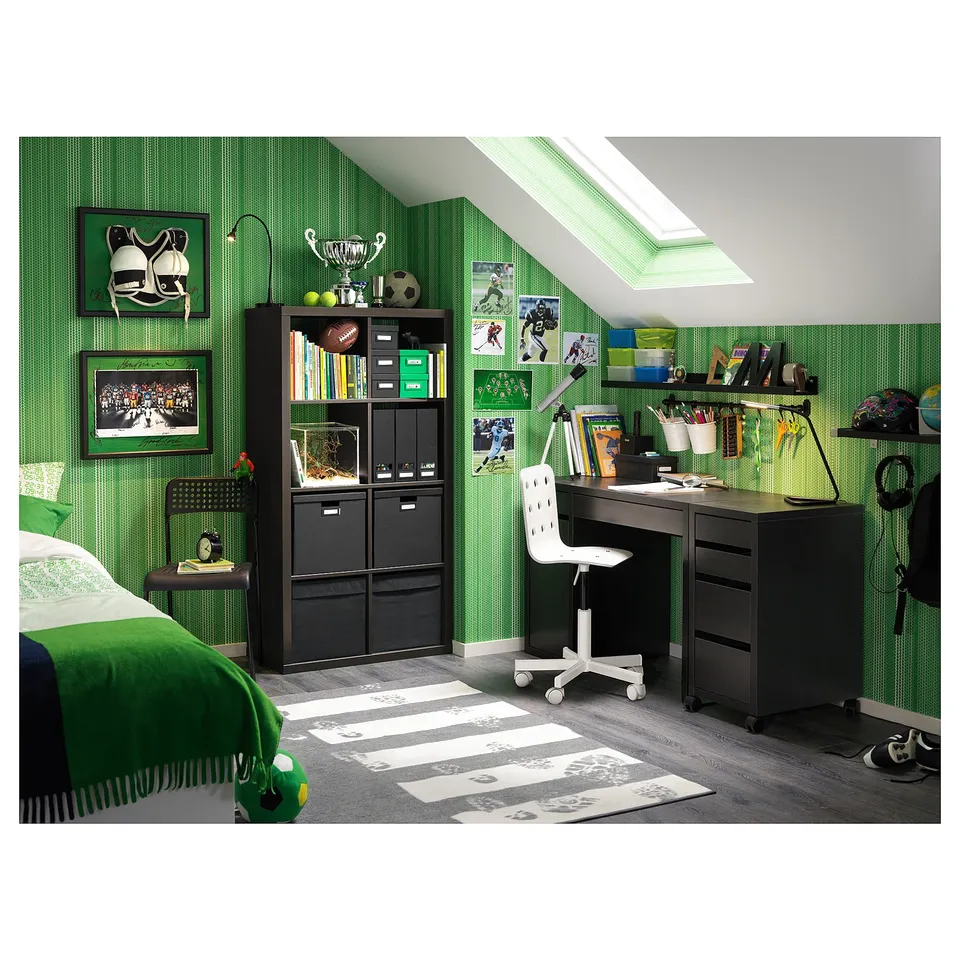 Cosy bedroom with green decor, sports theme, featuring MICKE black desk, shelves, and cabinets, plus a bed with green blanket.