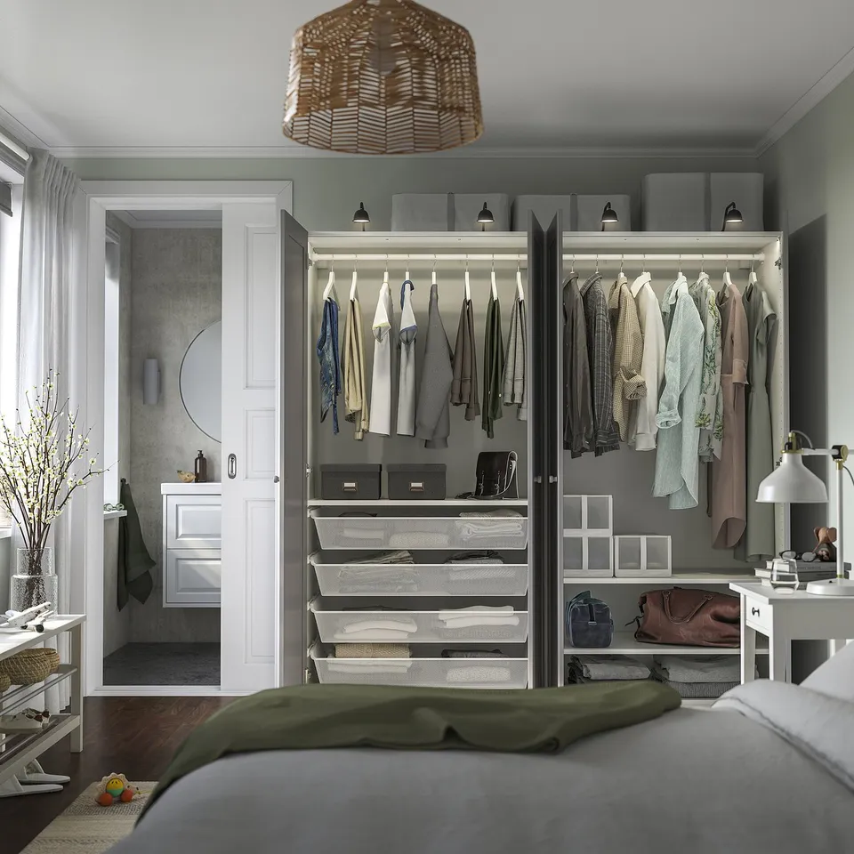 Bedroom with an open wardrobe displaying clothes, accessories, and shelves inside. A bathroom is visible through an open door.