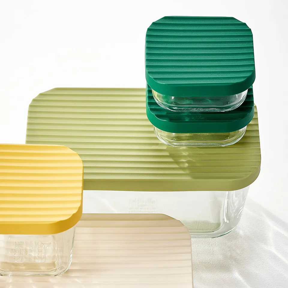 Three glass containers with colourful ridged lids, stacked neatly. Vibrant colours, good quality, durable and transparent.