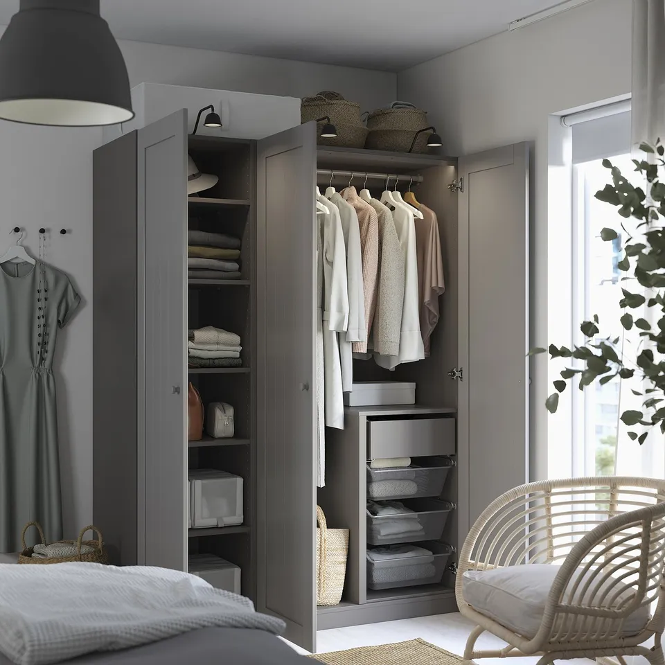 Bedroom closet with open doors revealing folded clothes, shelves, and drawers. Drapery and chair beside it.