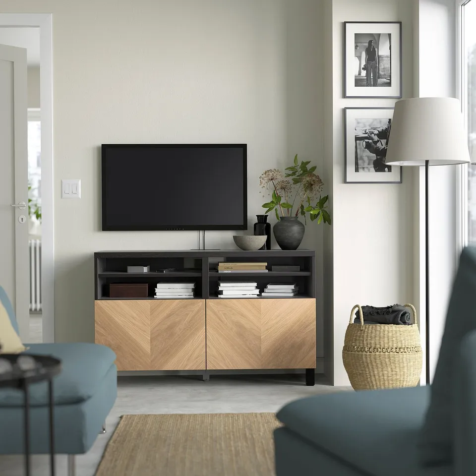 Modern living room with BESTÅ tv bench, tv, vases, photos, blue sofa, and wicker basket.