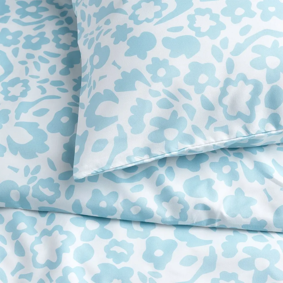 Close-up view of soft, patterned fabric with blue floral design on white background. Highlights texture and quality of recycled polyester material.
