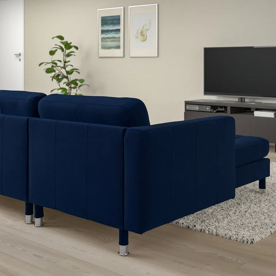 A modern living room with navy blue LANDSKRONA sofa against a wall, featuring a sleek design with metal legs. It sits near a tv and plant.