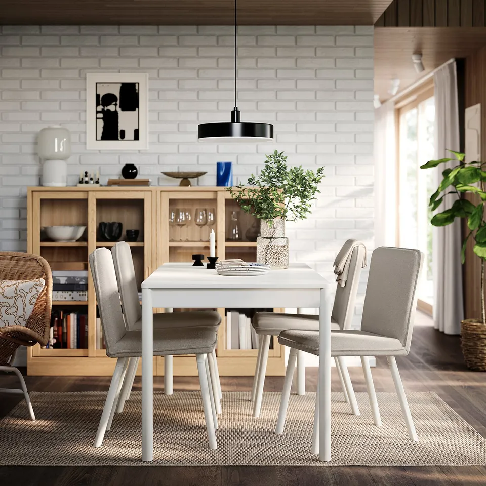Modern dining area with TONSTAD table, grey chairs, plant, and black pendant light. Sideboard with decor on left wall.