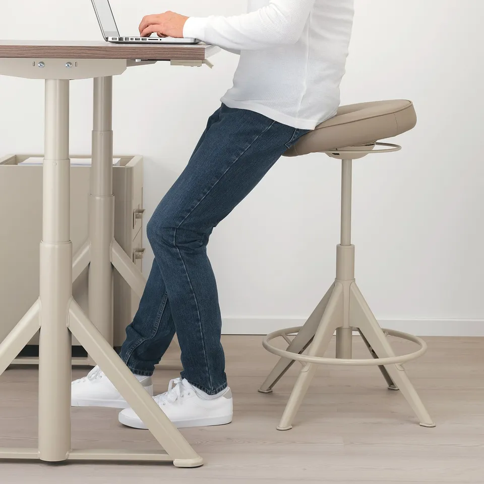 Person using sit/stand support at desk, promoting active seating and improved posture.