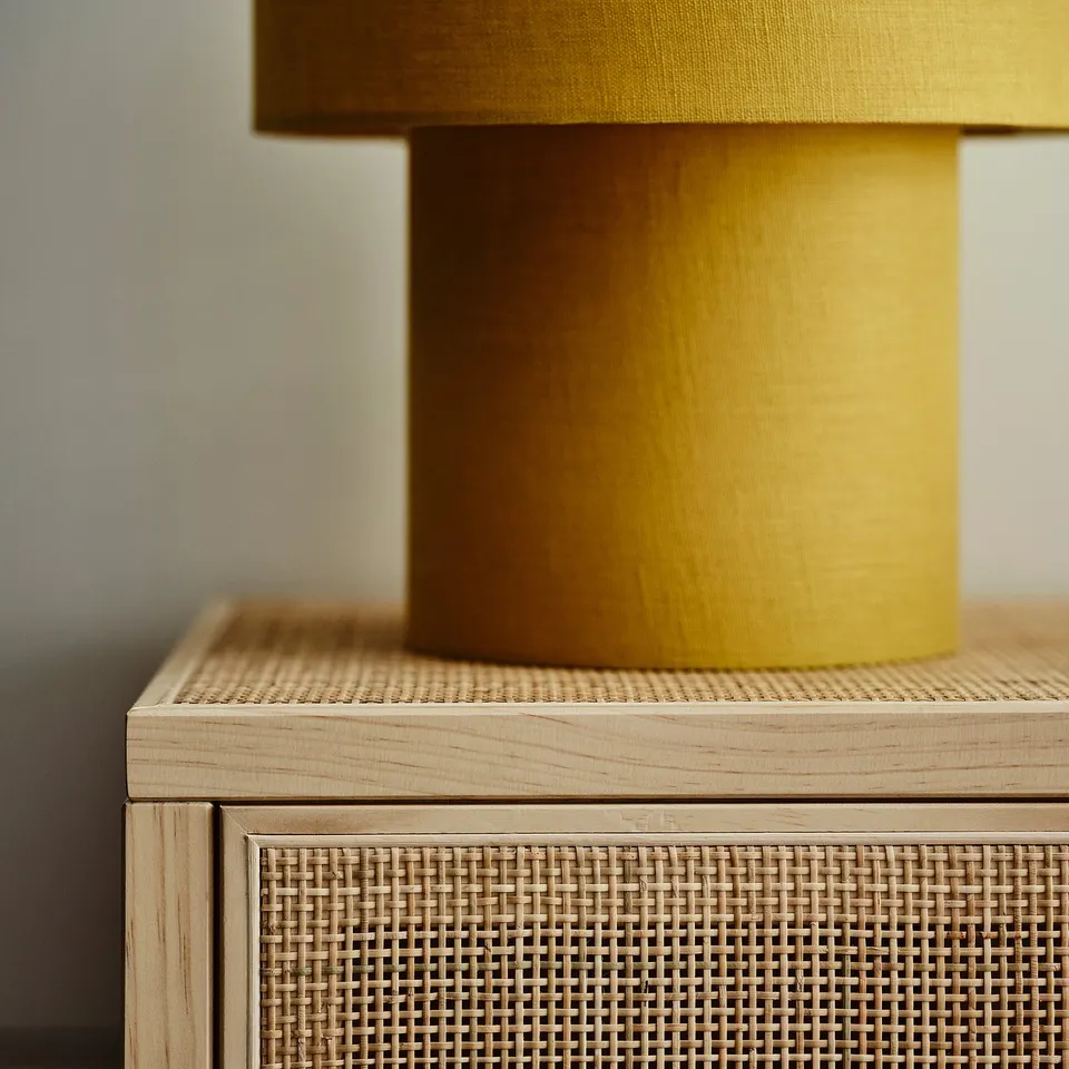 Stylish cabinet with woven front, wooden top & yellow lamp. Crafted with high-quality materials.