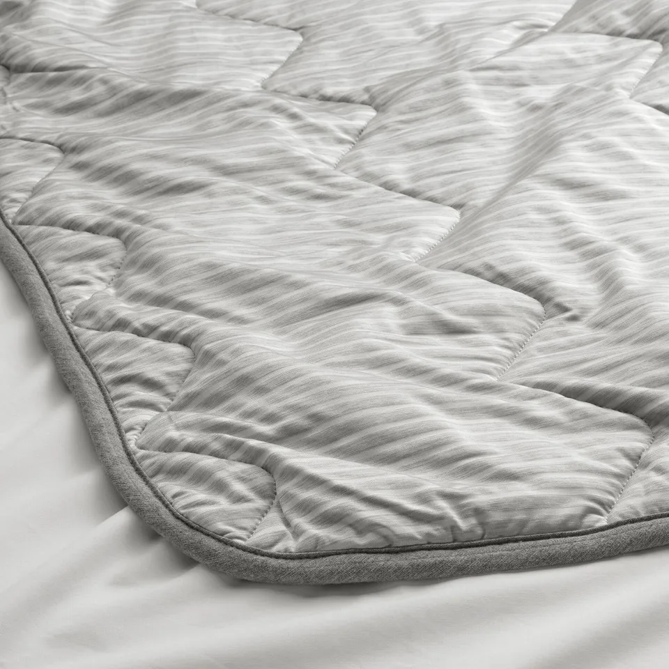 Duvet with cool, striped side and cosy jersey side, folded neatly, showcasing quality and comfort.