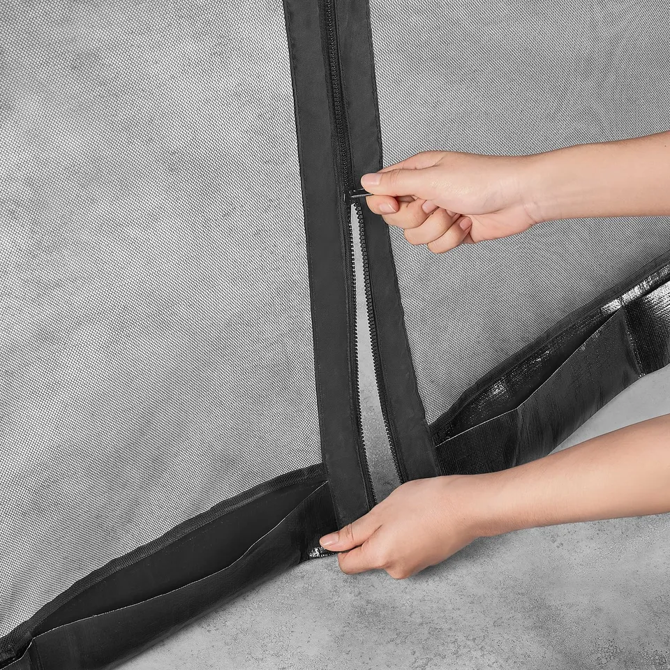 Person zips up a grey insect protection net with black borders on a mesh structure, securing it for outdoor use.