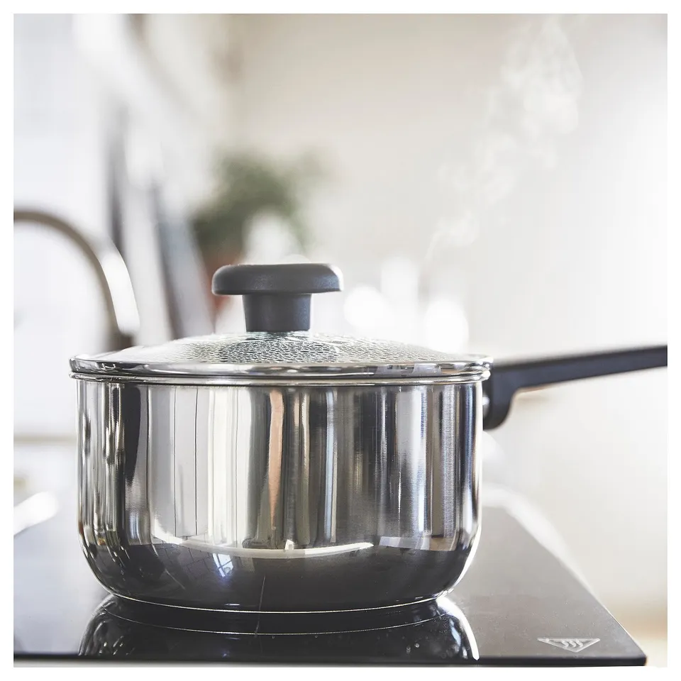 Silver saucepan with glass lid on stovetop. Easy cooking design.