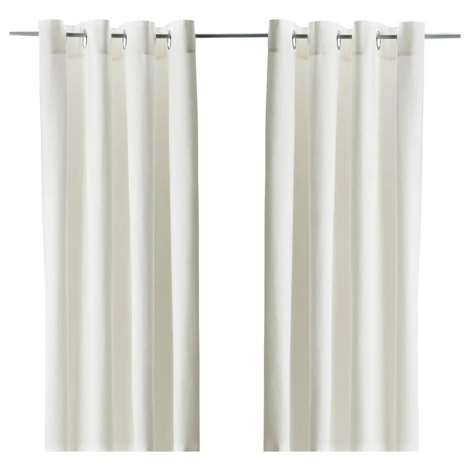 White MERETE curtains with eyelet headings, designed for room darkening and privacy. Made of 100% cotton, they hang straight.