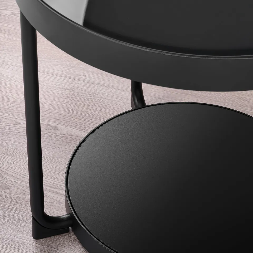 Modern black side table with round glass top and stylish metal legs. A sleek design and sturdy construction.