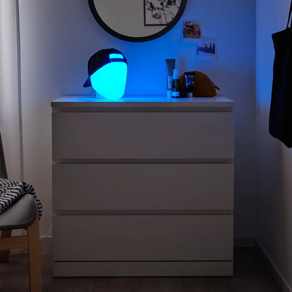 Grey ISKÄRNA dresser with blue lamp, mirror, and personal items, styled for bedroom.