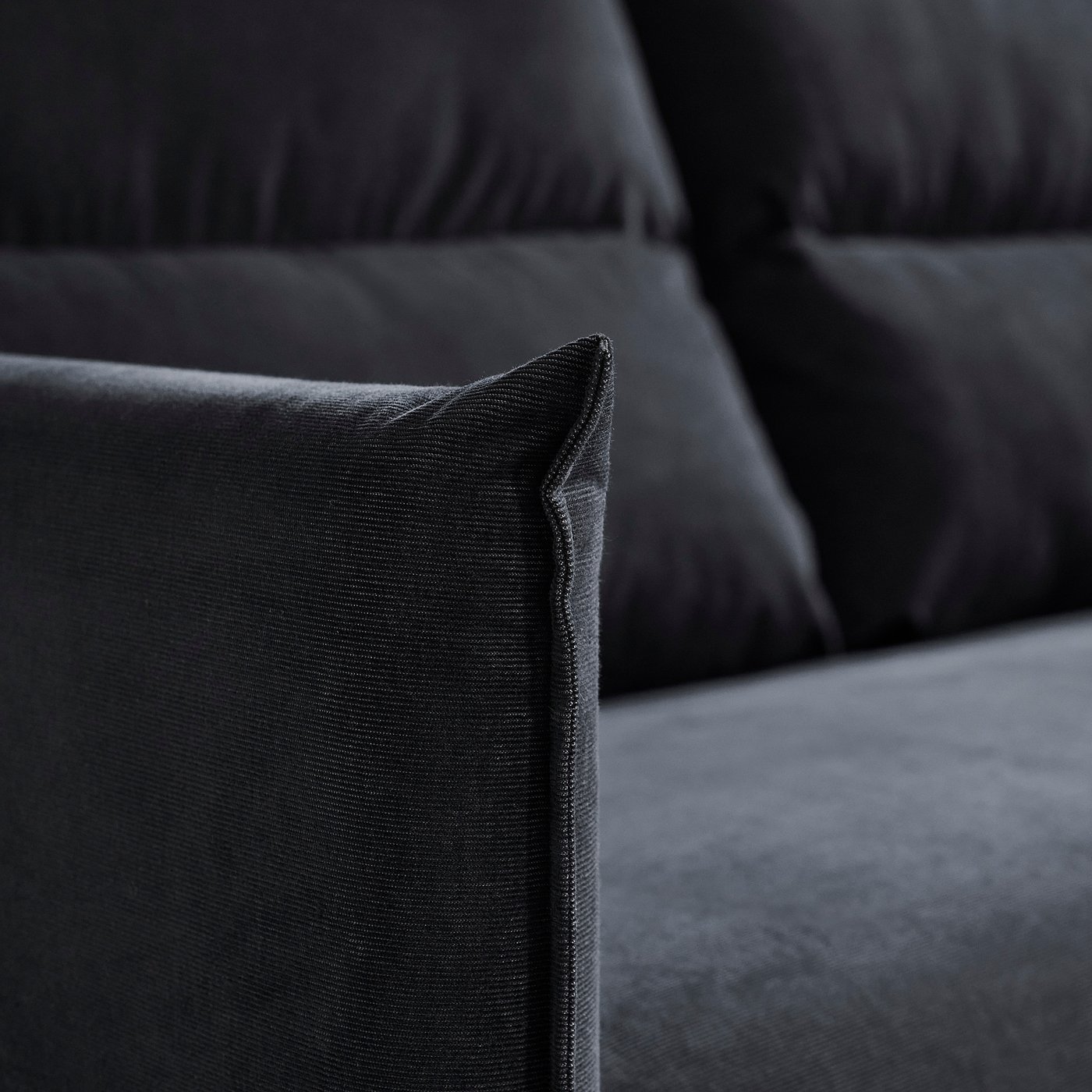 Close-up of dark grey sofa, showing plush cushions and sleek upholstery detail.