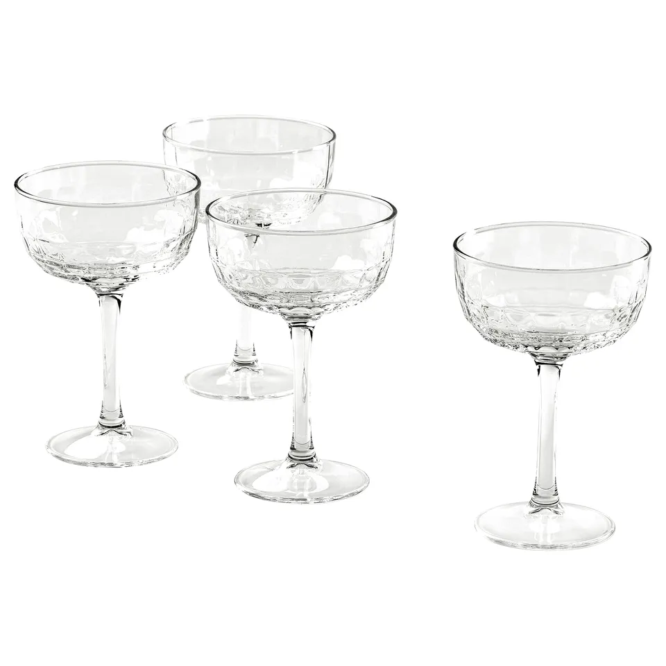 Four clear glass FRÖJDA coupes, elegant and timeless, perfect for champagne or cocktails, faceted design, wide and low shape.