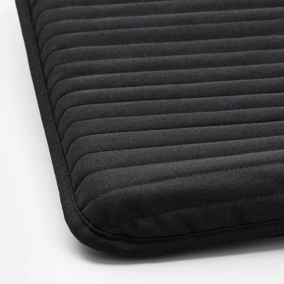 Black cushioned footstool with ribbed texture, featuring upholstery and upholstered underside, showcasing quality design and comfort.