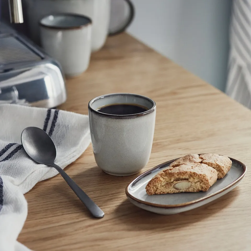 Cup of coffee with biscotti on wooden table.