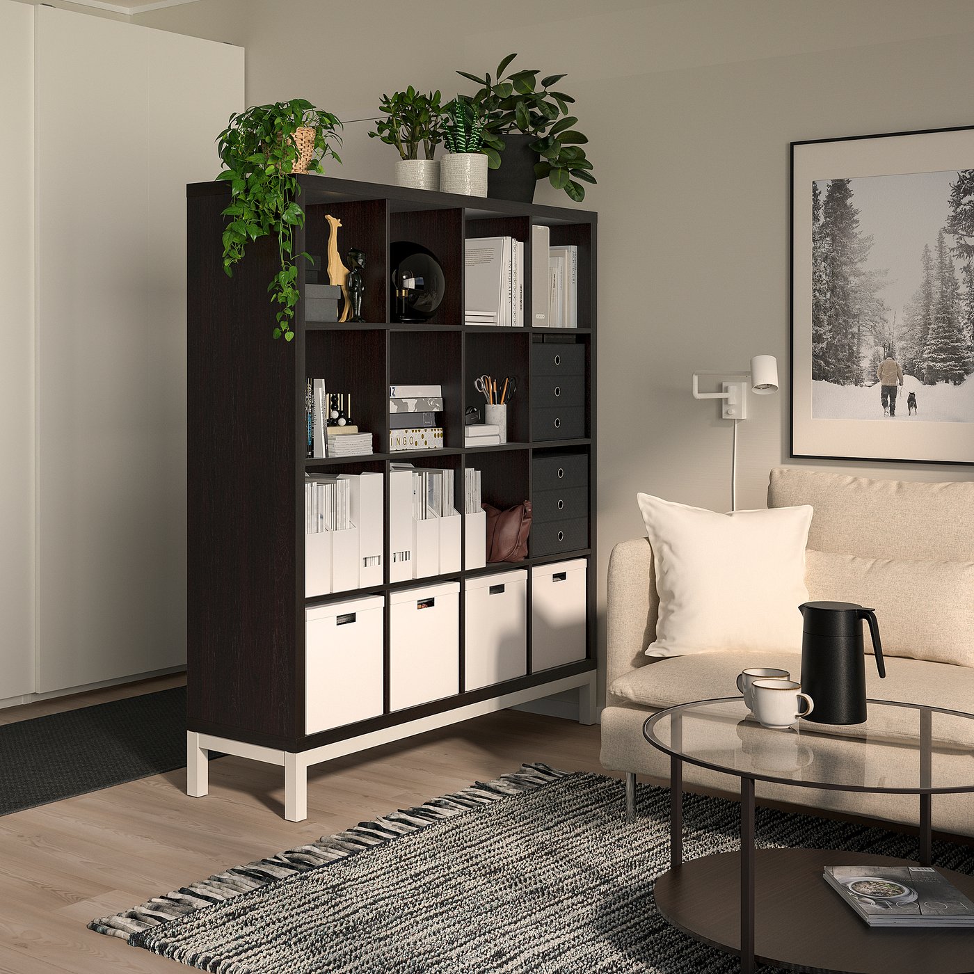 Living room with KALLAX divider, plants, decor. Armchair, coffee table, rug, art.