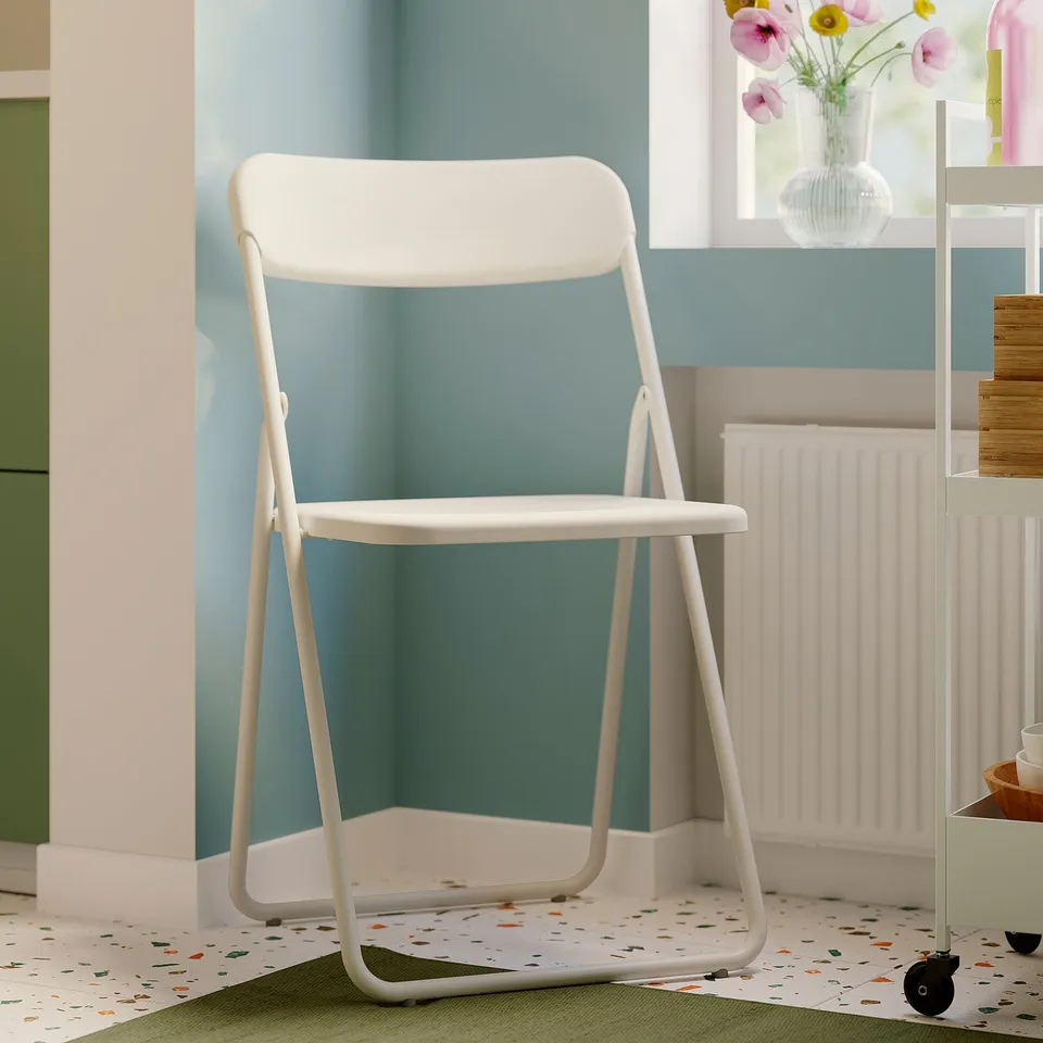 GUNDE folding chair with metal frame and plastic seat, near radiator with flowers.