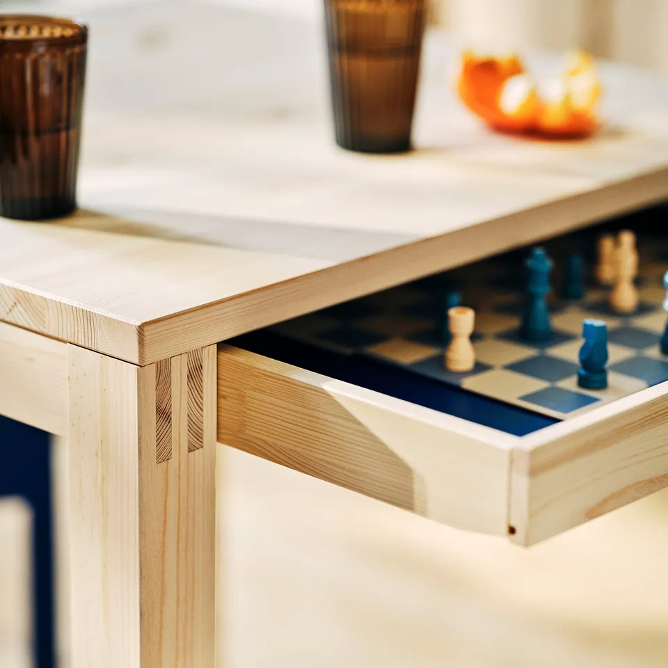 Chess set on elegant wooden table with drawer.