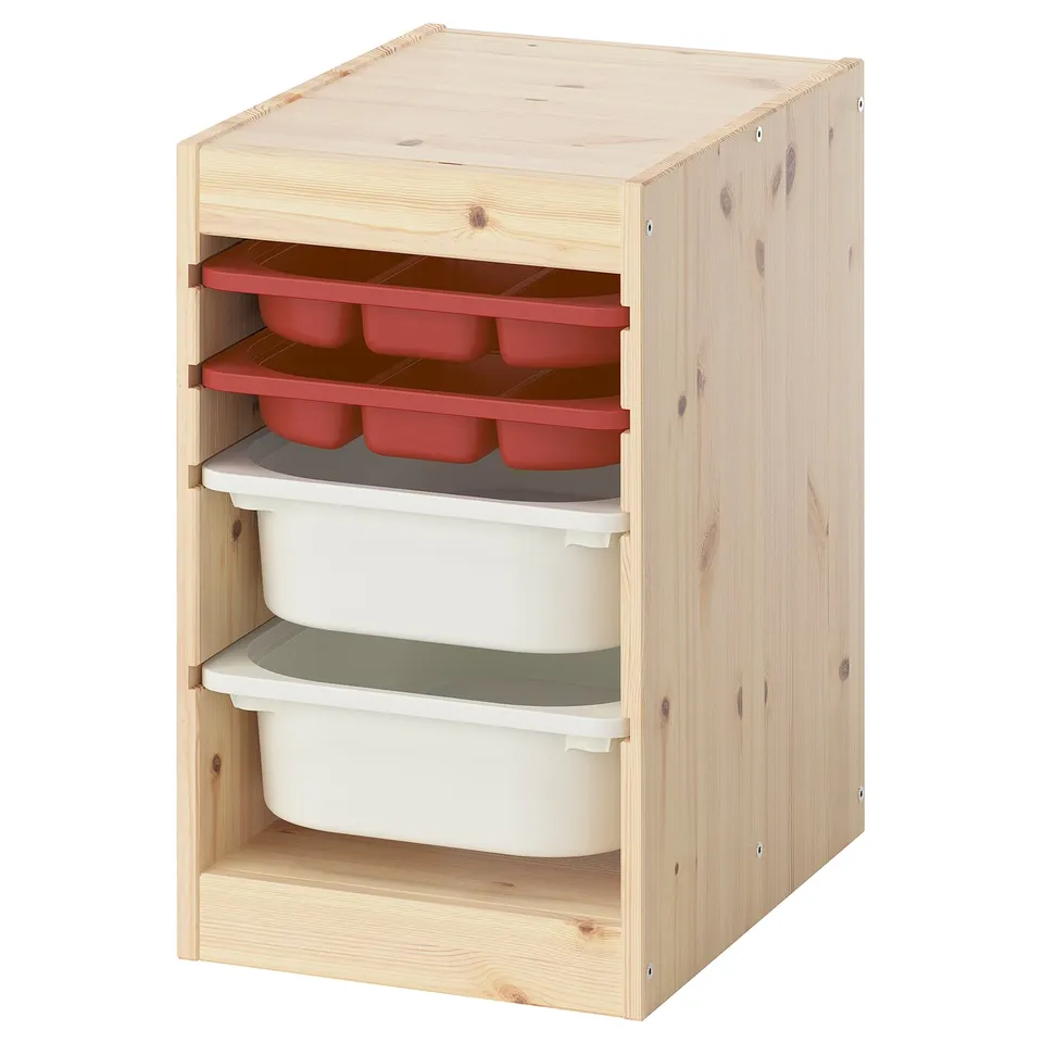 A TROFAST light wood storage unit with red and white plastic bins and trays for organising childrens items.