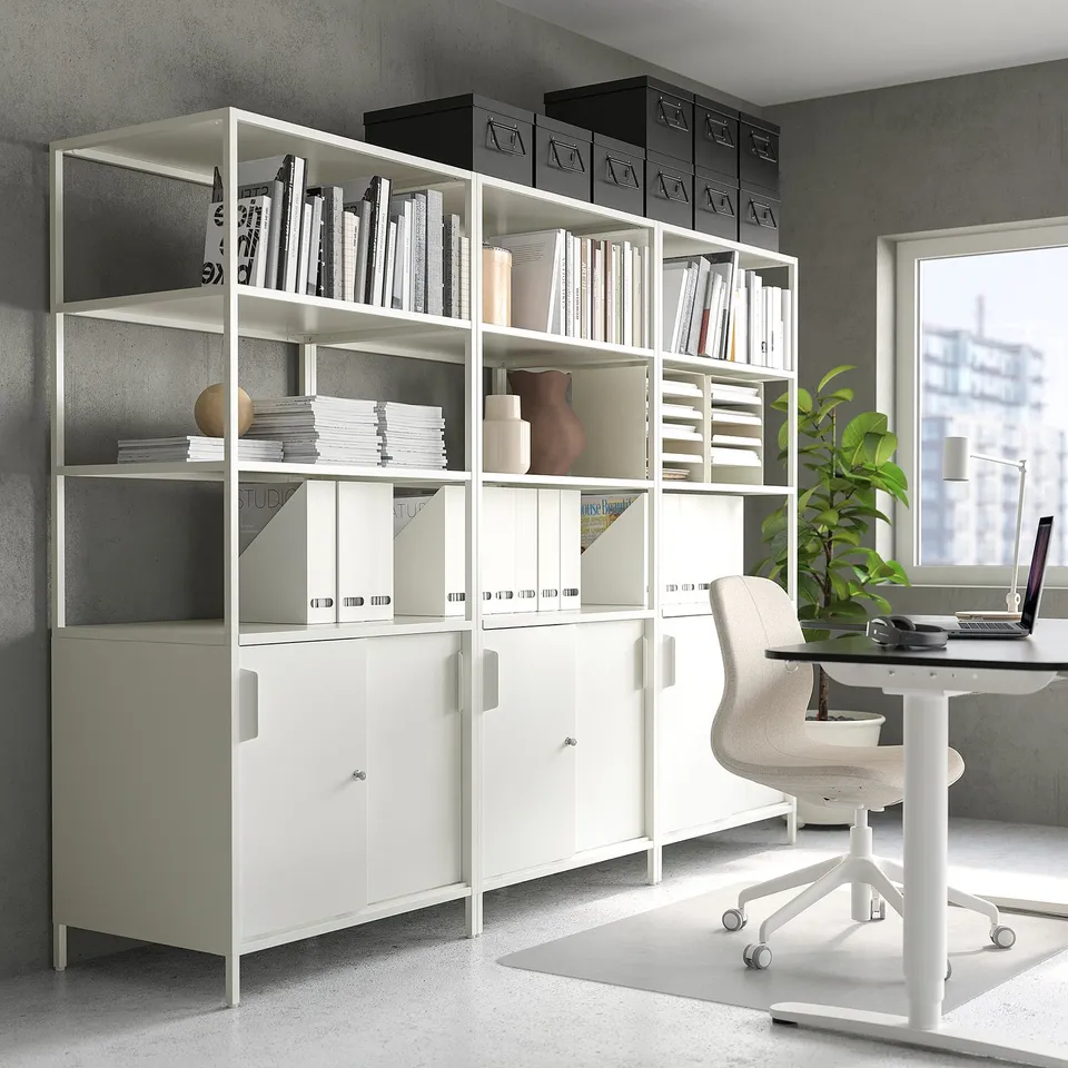 White TROTTEN double-sided office cabinet with shelves and storage, chair, and plant.