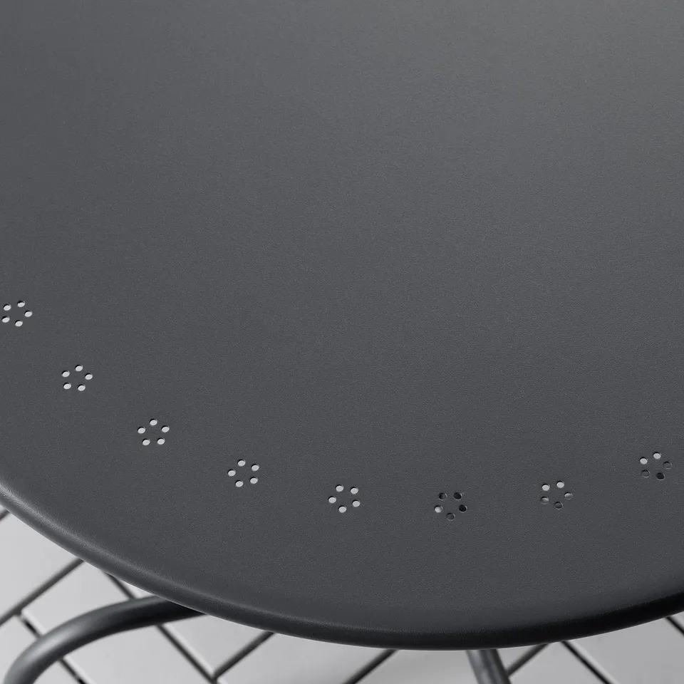 Dark outdoor table with metal frame, featuring evenly spaced circular patterns on its surface.