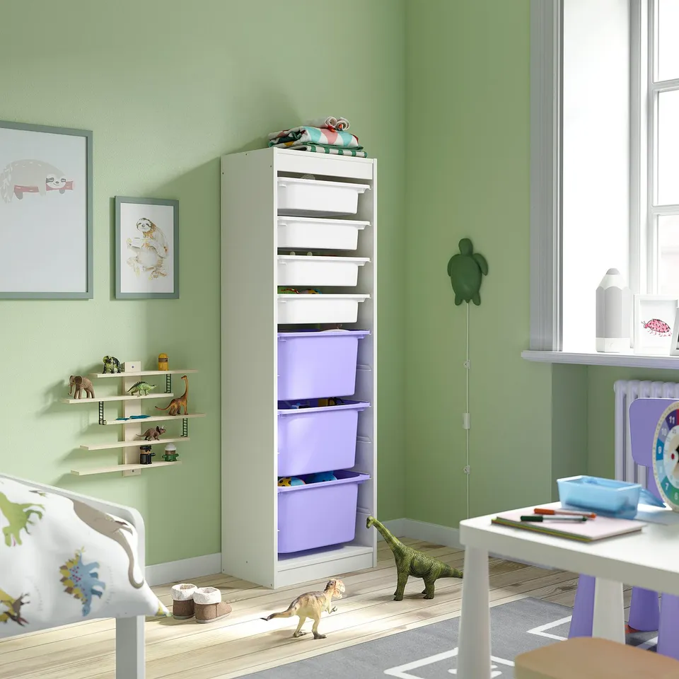 Childs room with white TROFAST storage unit, purple bins, dinosaur toys, wall art, desk, and bed.