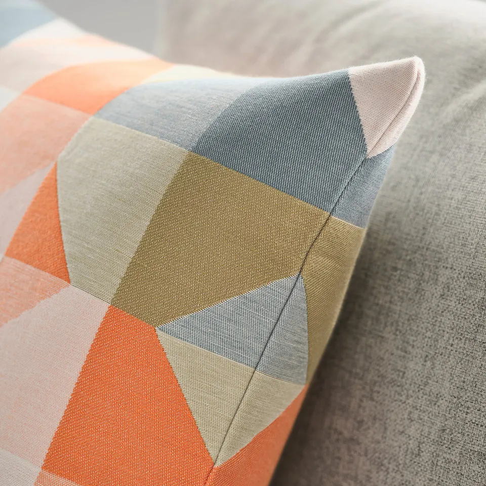 Close-up of cushion cover with colourful geometric pattern, soft texture, subtle relief design.
